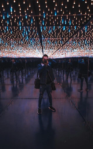 a man standing in a room filled with lights, by Carey Morris, unsplash contest winner, interactive art, hall of mirrors, snapchat photo, wide full body, cool skydome