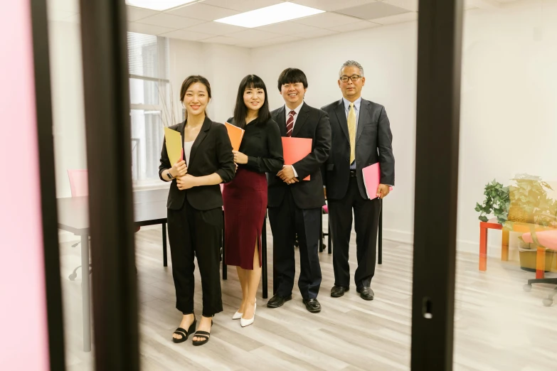 a group of people standing next to each other, in an office, hidetaka miyazaki, background image, professional image