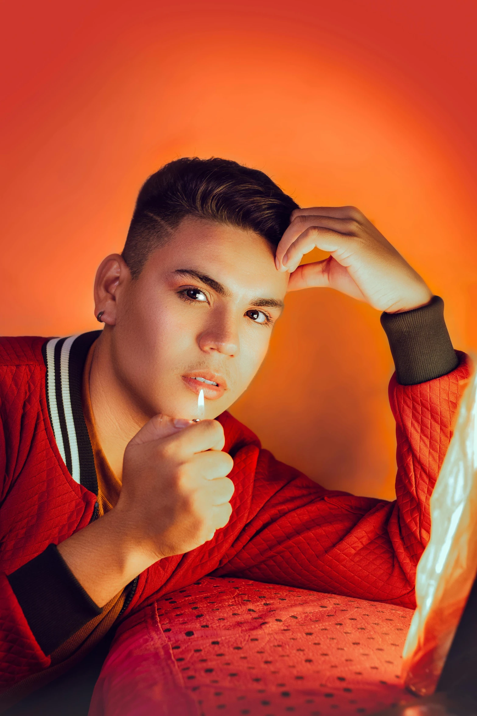 a man sitting in front of a laptop computer, an album cover, inspired by Randy Vargas, trending on pexels, light stubble with red shirt, nonbinary model, cigarette, confident pose