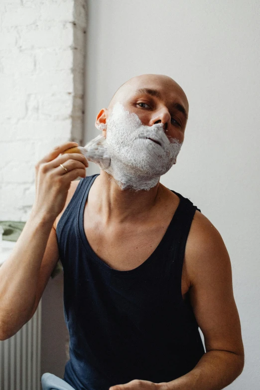 a man shaving his face in front of a window, inspired by Edi Rama, reddit, silicone skin, covered in white flour, on grey background, bedhead