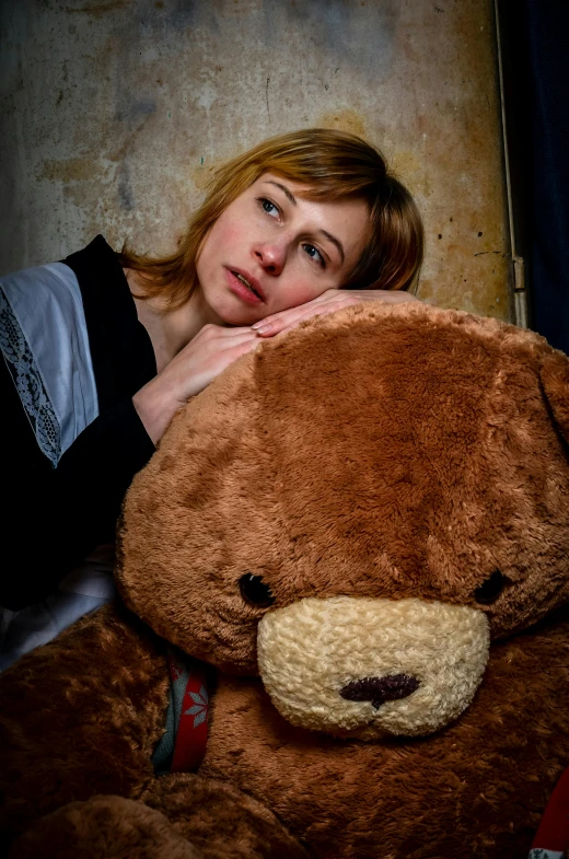 a woman laying next to a large teddy bear, a stock photo, by Adam Marczyński, trending on reddit, depressed sad expression, closeup portrait, concerned expression, brown