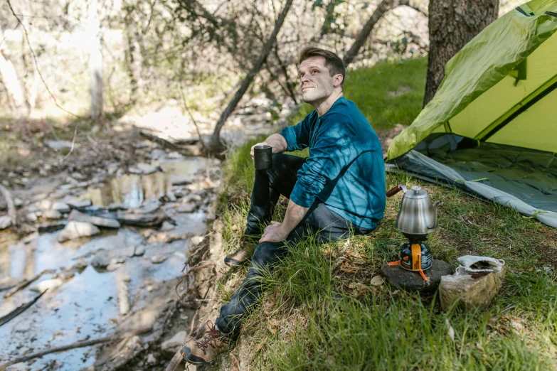 a man sitting on the ground next to a tent, a portrait, by Meredith Dillman, unsplash, peacefully drinking river water, avatar image, hiking clothes, full length photo