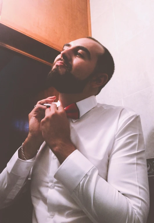 a man in a white shirt tying a red bow tie, featured on reddit, les nabis, arab man light beard, profile image, nights, professional profile picture