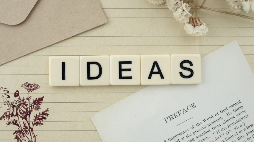 a book sitting on top of a table next to a bunch of flowers, a cartoon, trending on pexels, verdadism, lightbulb, made of all white ceramic tiles, writing a letter, beige