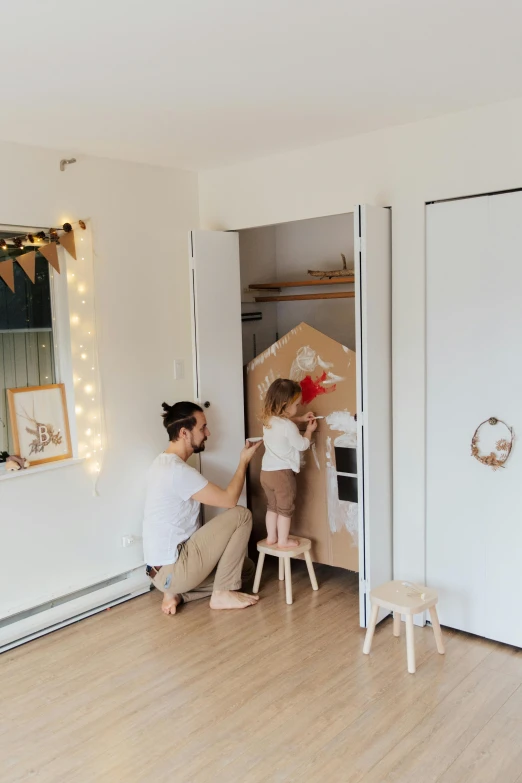 a couple of people that are in a room, by Nicolette Macnamara, pexels contest winner, childs bedroom, white broom closet, wooden decoration, daddy/fatherly