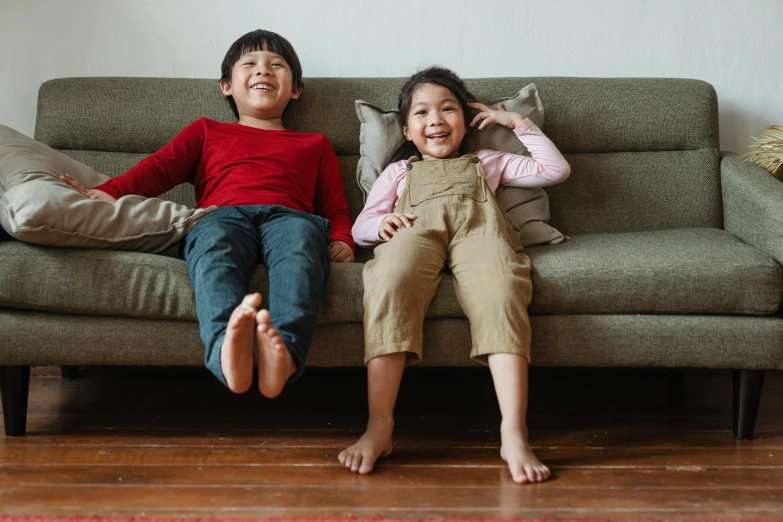 a couple of kids sitting on top of a couch, pexels, red shirt brown pants, asian descent, joyful people in the house, aaaaaaaaaaaaaaaaaaaaaa