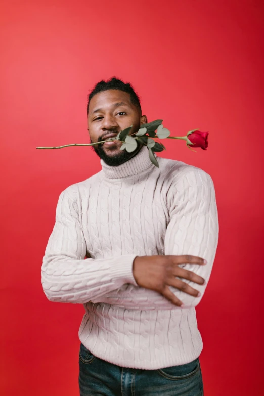 a man with a rose in his mouth on a red background, trending on pexels, jemal shabazz, on a gray background, he is wearing a brown sweater, holding a flower