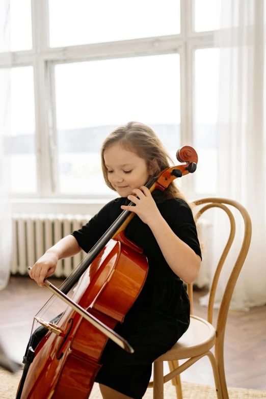 a little girl sitting on a chair playing a cello, pexels contest winner, greta thunberg, 15081959 21121991 01012000 4k, promotional image, soft natural light