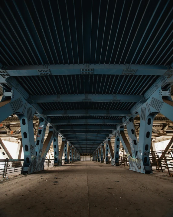 a view of the underside of a bridge, an album cover, unsplash contest winner, brutalism, blue, interior of a huge robot factory, panoramic anamorphic, high resolution photo