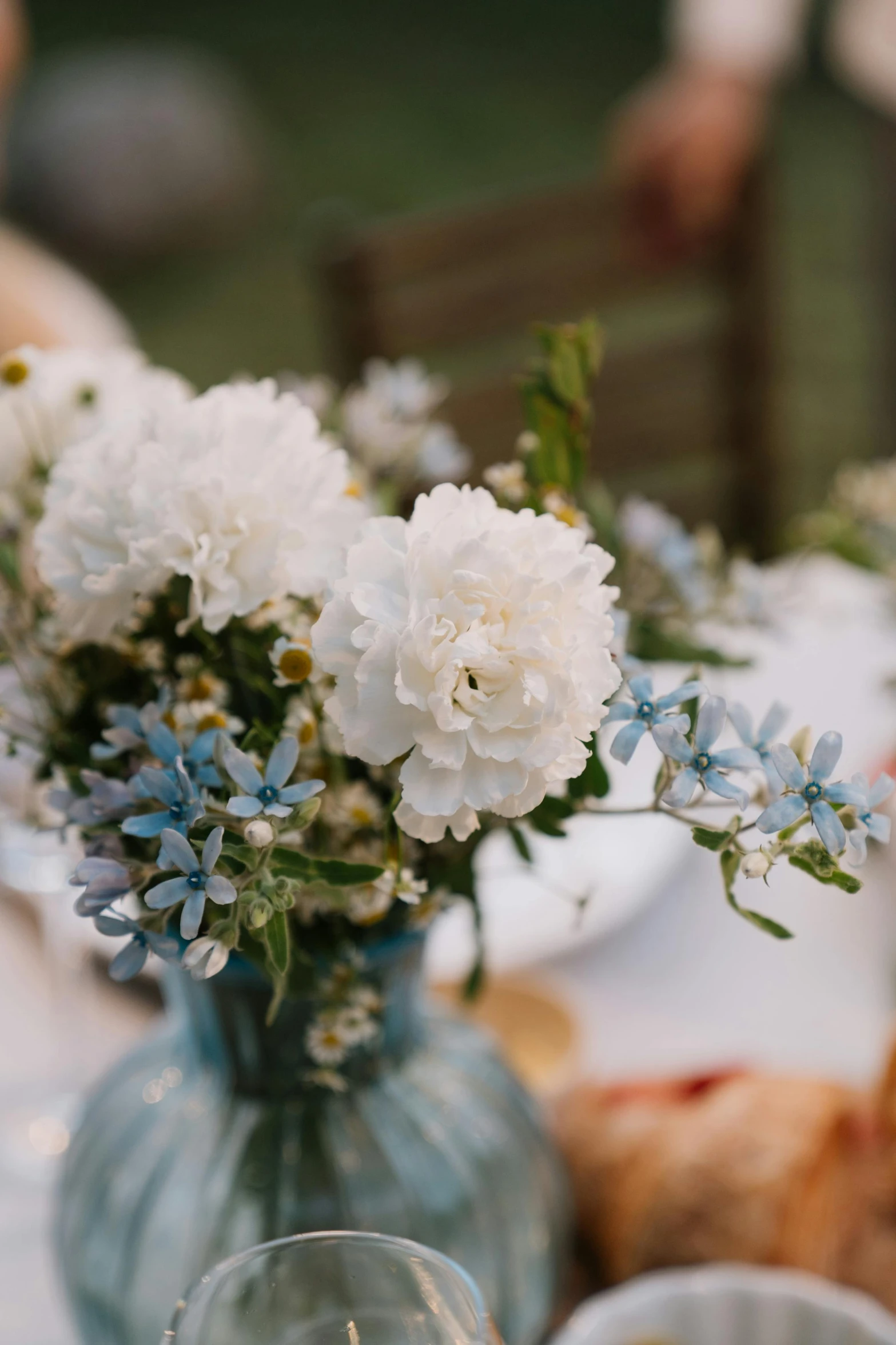 a vase filled with white flowers sitting on top of a table, by Jessie Algie, unsplash, amber and blue color scheme, al fresco, celebration, detail shot