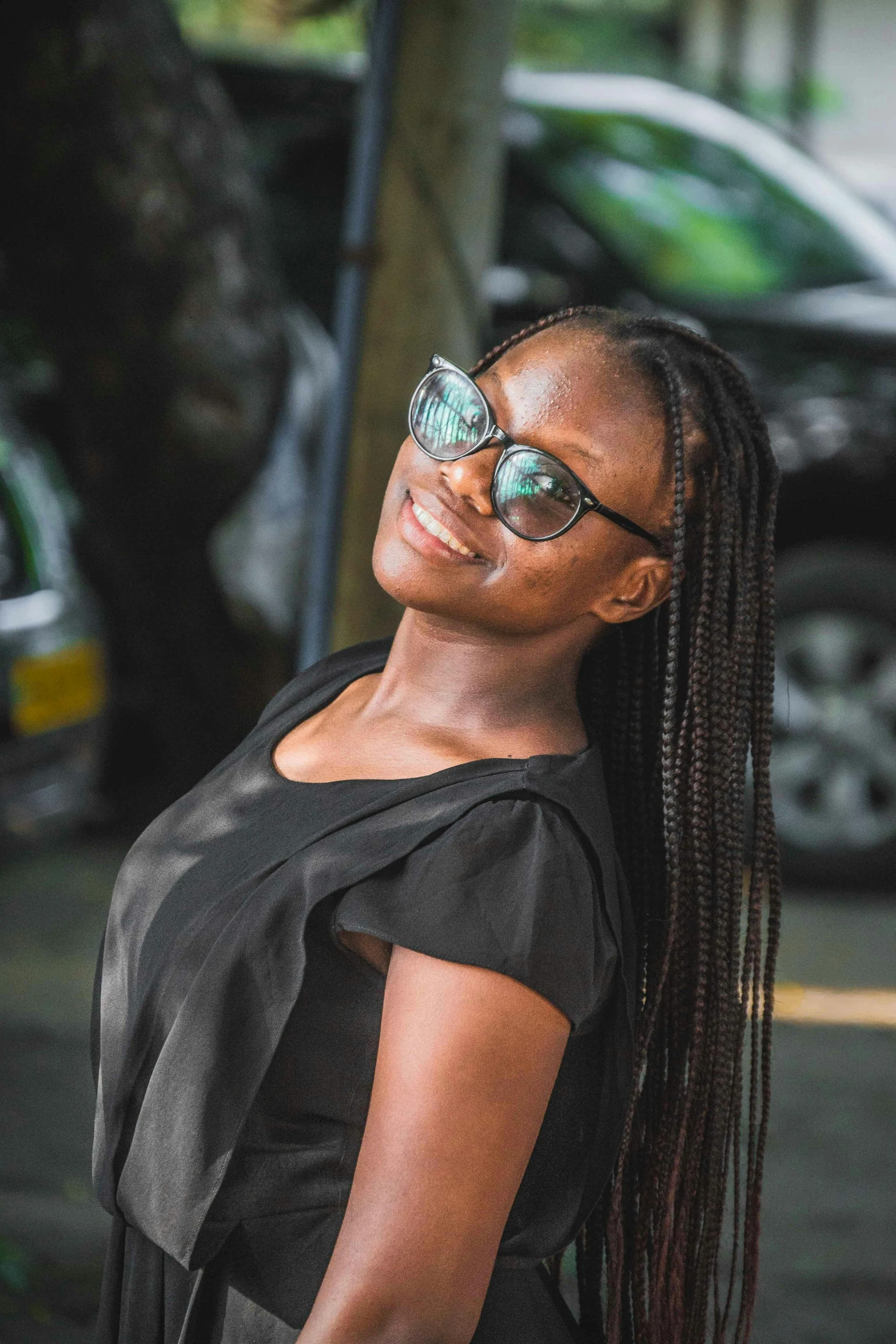 a woman in a black dress and sunglasses smiles at the camera, by Chinwe Chukwuogo-Roy, pexels contest winner, hurufiyya, slight nerdy smile, avatar image, multiple stories, uploaded