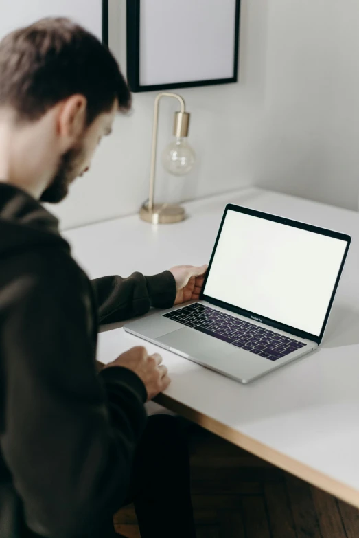 a man sitting at a desk using a laptop computer, trending on pexels, sitting in an empty white room, holding glowing laptop computer, rounded corners, carson ellis