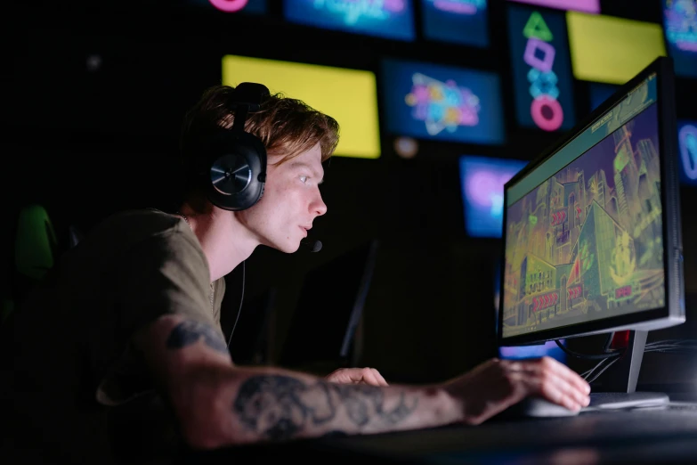 a man sitting in front of a computer with headphones on, video game assets, colorful computer screen, night shot, profile image