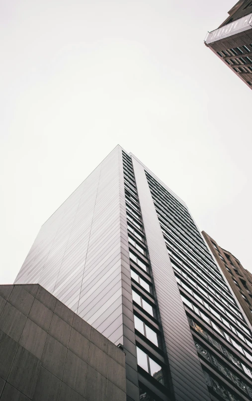 a couple of tall buildings next to each other, a photo, unsplash, modernism, gray sky, exterior photo, metallic architecture, high picture quality