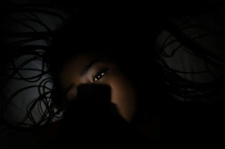 a close up of a person holding a cell phone, by Alexis Grimou, shadowy cat under the bed', black girl, backlit face, ☁🌪🌙👩🏾