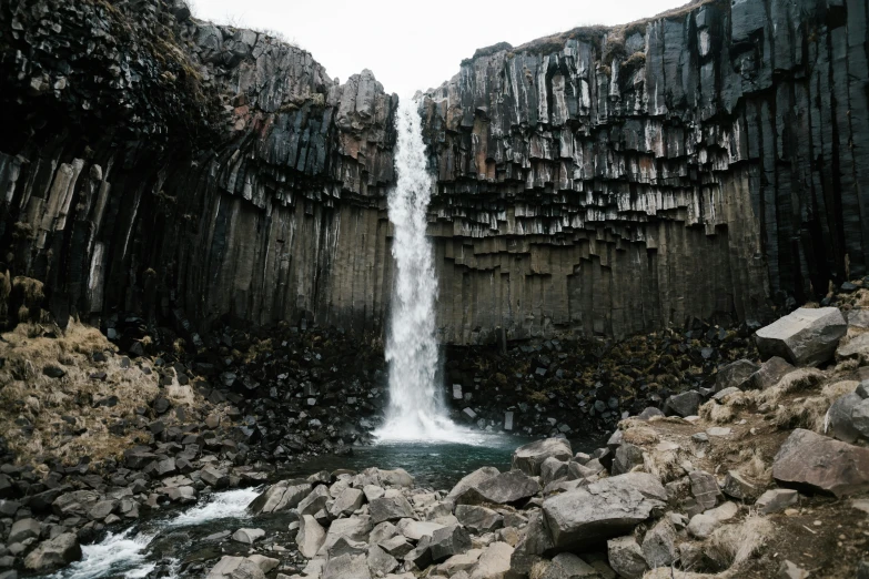 a waterfall in the middle of a rocky area, by Hallsteinn Sigurðsson, unsplash contest winner, hurufiyya, tall castle enclosed palisaded, tessellated planes of rock, hyperrealism photo, structural geology