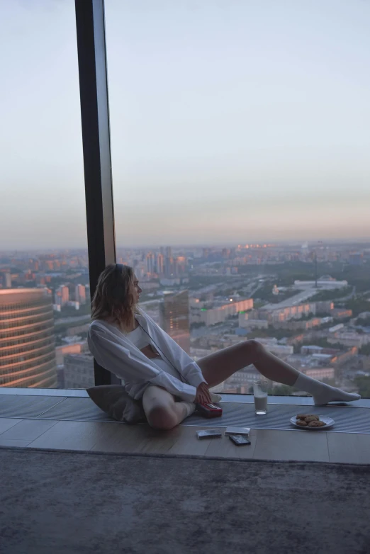 a woman sitting on top of a window sill, by Emma Andijewska, happening, with tall glass skyscrapers, gta in moscow, low quality photo, sunset photo