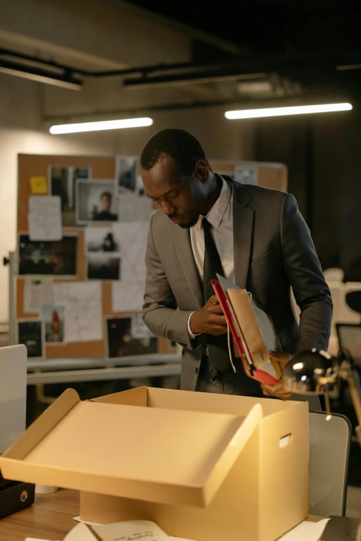 a man in a suit standing next to a box, pexels contest winner, production still, black man, working in an office, sentimental