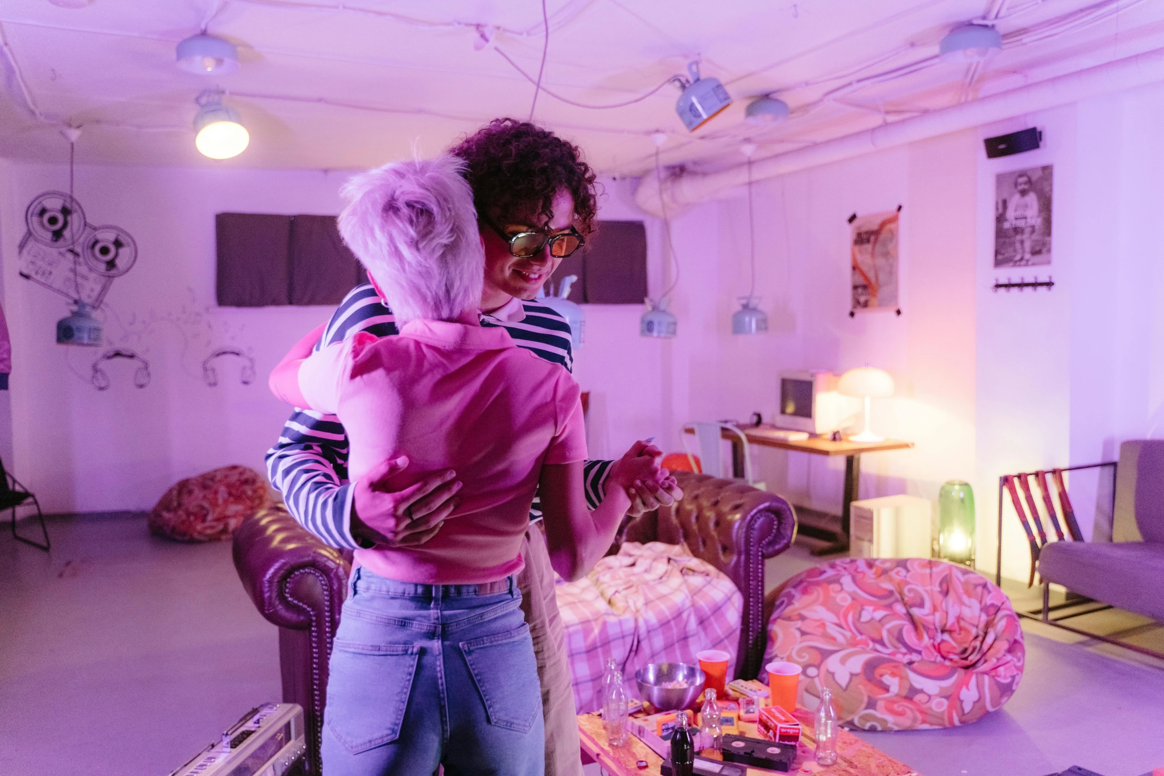 a couple of people that are standing in a room, pexels, happening, lesbian embrace, brightly lit purple room, charli bowater and artgeem, slide show