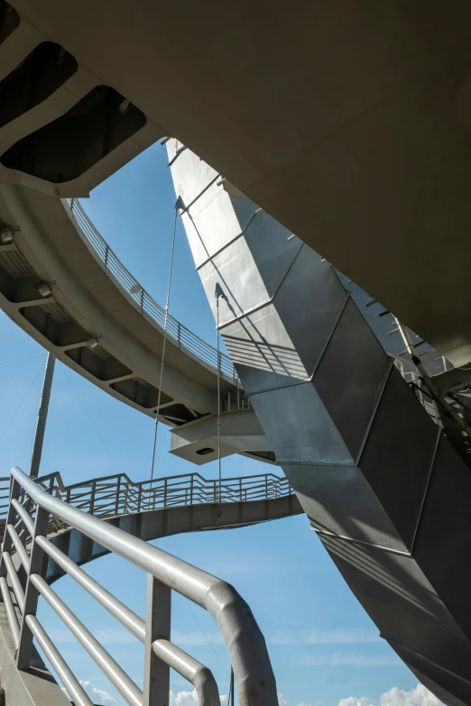 a man riding a skateboard up the side of a ramp, an abstract sculpture, inspired by Zaha Hadid, unsplash, brutalism, steel archways, monorail, view from bottom to top, stainless steel