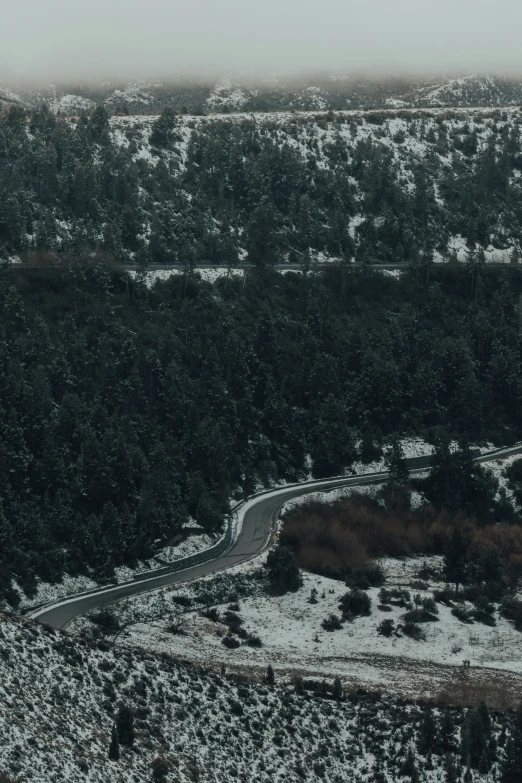 an aerial view of a winding mountain road, an album cover, by Pablo Rey, low quality grainy, winter photograph, grey, panorama