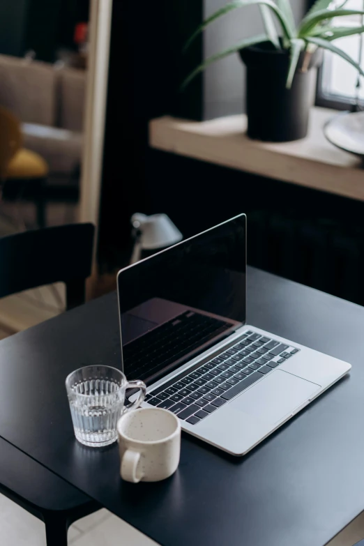 a laptop computer sitting on top of a wooden table, trending on pexels, table in front with a cup, looking serious, college, with a black background