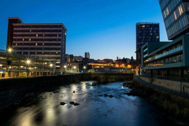 a river running through a city next to tall buildings, inspired by Edwin Georgi, unsplash, hurufiyya, chesterfield, twilight ; wide shot, yorkshire, wellington