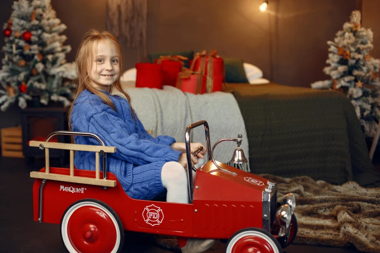 a little girl that is sitting in a toy car, in front of a fireplace, official product photo, fireman, square