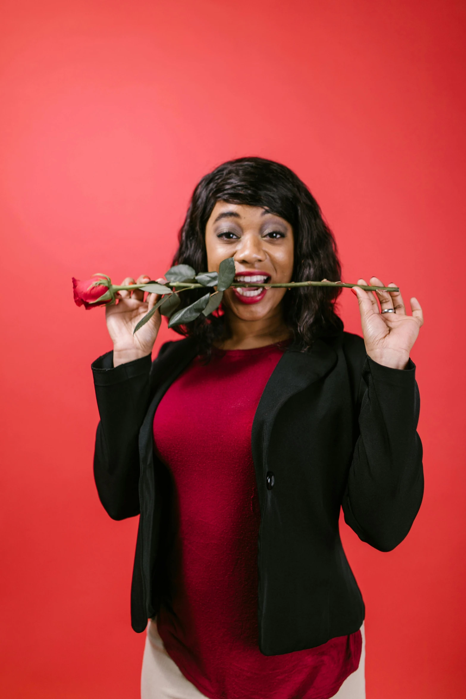 a woman holding a rose in front of her face, an album cover, pexels contest winner, holding a gold! cane!, plain background, playful smirk, ebony