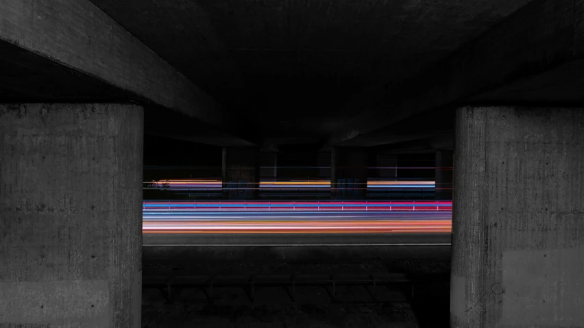 a black and white photo of a street at night, inspired by Andreas Gursky, unsplash, conceptual art, colored lasers, sitting under bridge, multi - coloured, speed