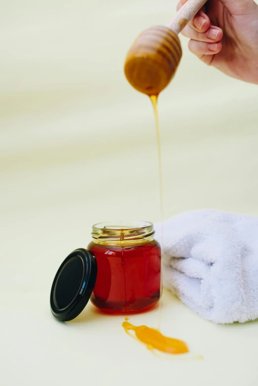 a person holding a wooden spoon over a jar of honey, by Elizabeth Durack, unsplash, process art, spa, robe, manicured, thumbnail