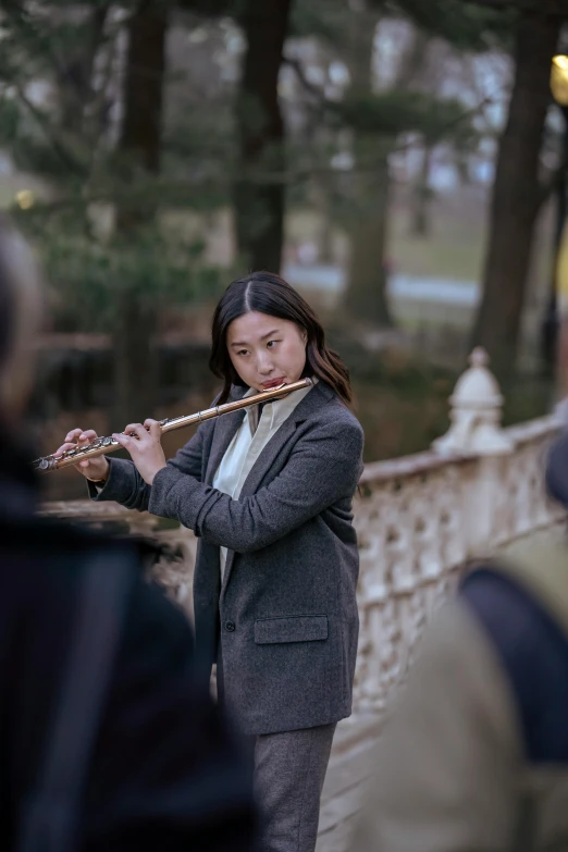 a woman playing a flute on a bridge, an album cover, inspired by Feng Zhu, pexels contest winner, realism, central park, movie still, performance, promo still