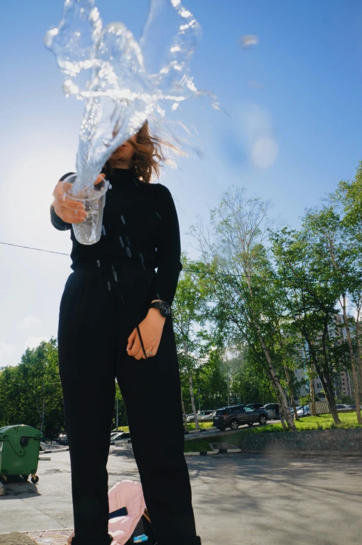 a woman standing on top of a skateboard next to a fire hydrant, pexels contest winner, wearing a black catsuit, holding a bottle of arak, there is water splash, gif
