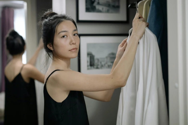 a woman that is standing in front of a mirror, wearing clothes