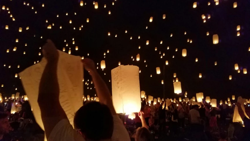 a group of people holding up paper lanterns in the air, ☁🌪🌙👩🏾, fireflys, avatar image