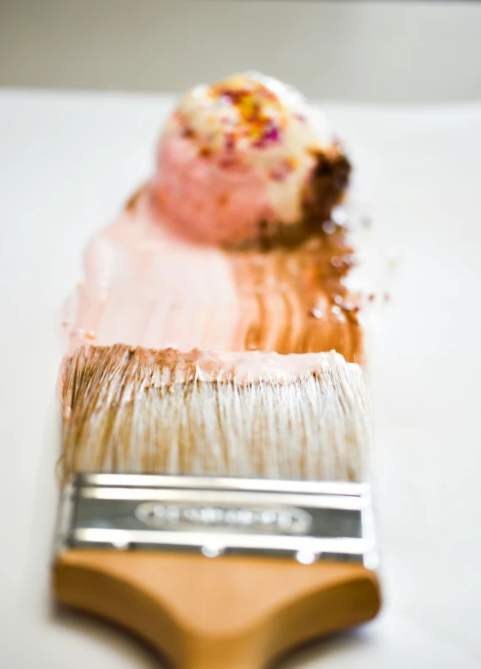 a close up of a paint brush on a table, a photorealistic painting, inspired by Cy Twombly, pexels, strawberry ice cream, brushed rose gold car paint, food photography gourmet, an intricate