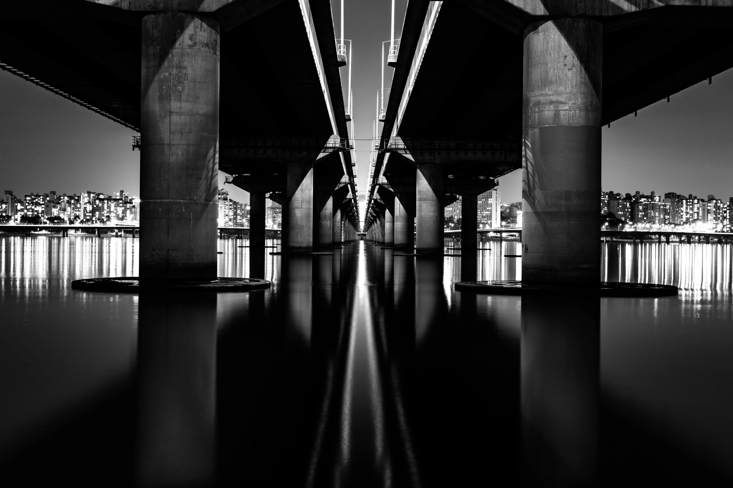 a black and white photo of a bridge at night, by Brad Holland, unsplash contest winner, minimalism, hyperrealistic symmetrical 8k, waterline refractions, detailed medium format photo, twins