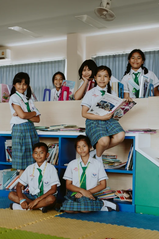 a group of children in school uniforms posing for a picture, by Anna Findlay, pexels contest winner, book shelf small library, thai, panoramic shot, slide show