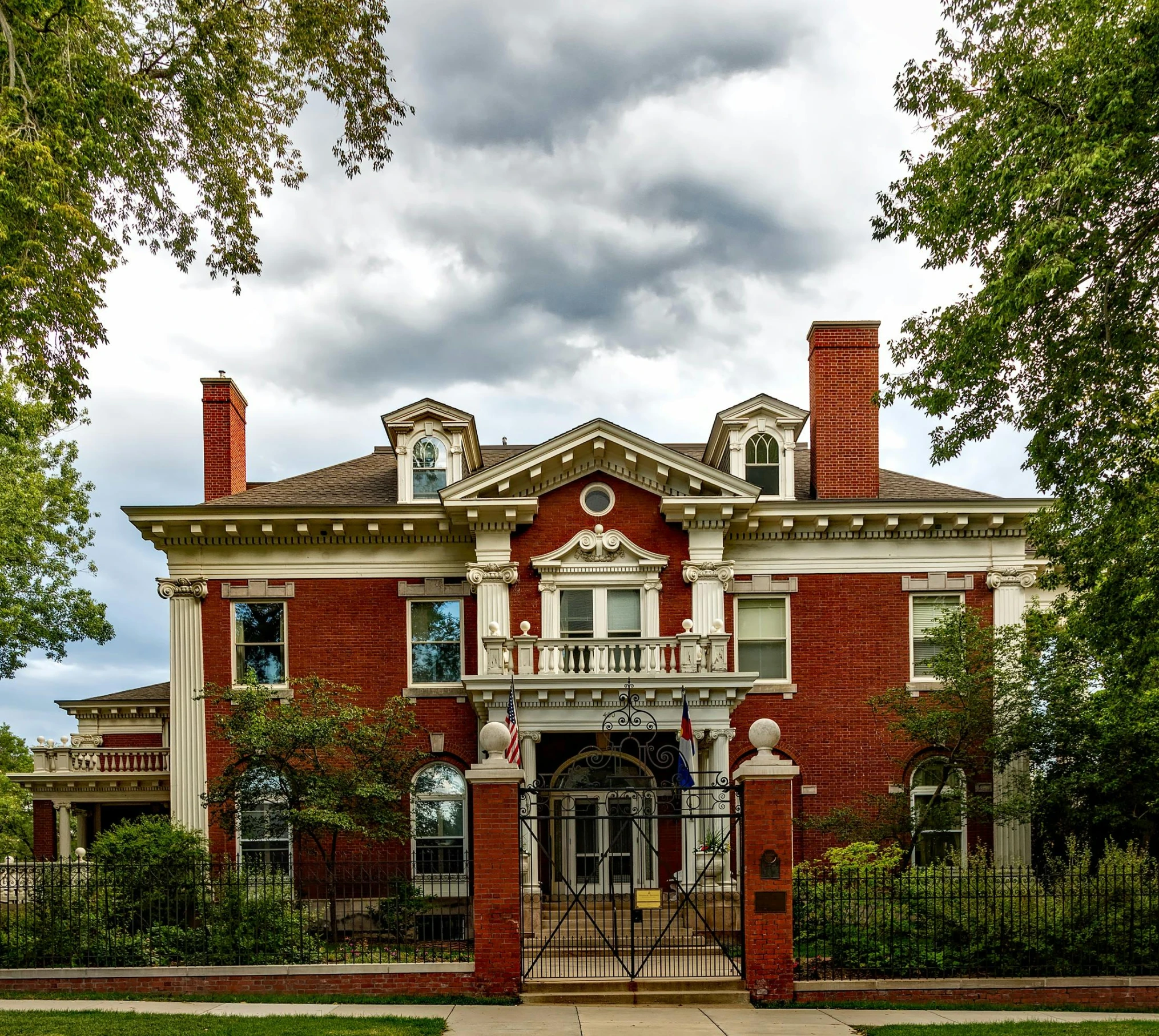 a large brick building with a gate in front of it, pexels contest winner, richly decorated victorian house, colorado, thumbnail, neo classical architecture