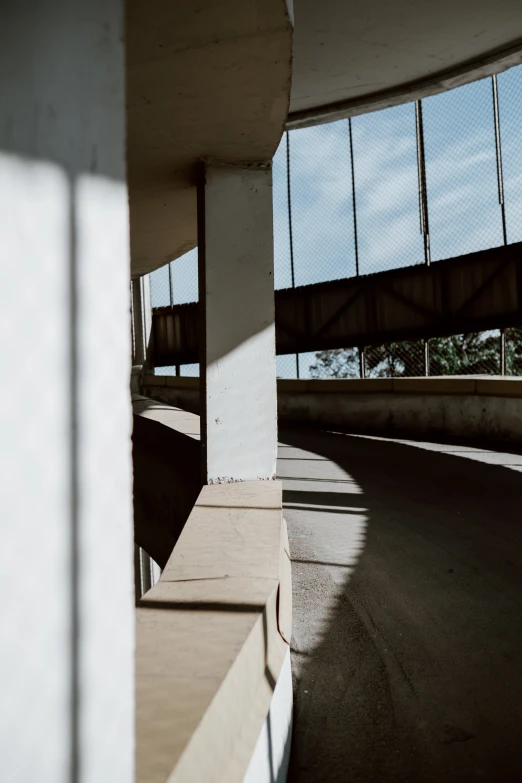 a man riding a skateboard up the side of a ramp, inspired by Ned M. Seidler, unsplash, brutalism, low quality photo, overpass, shadows, white building