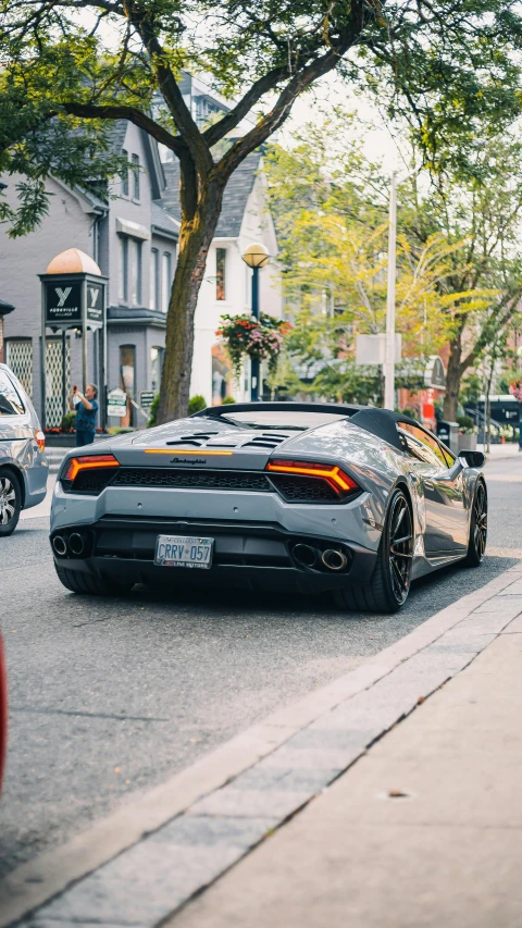 a silver sports car driving down a city street, pexels contest winner, renaissance, toronto, lamborghini, back, color ( sony a 7 r iv