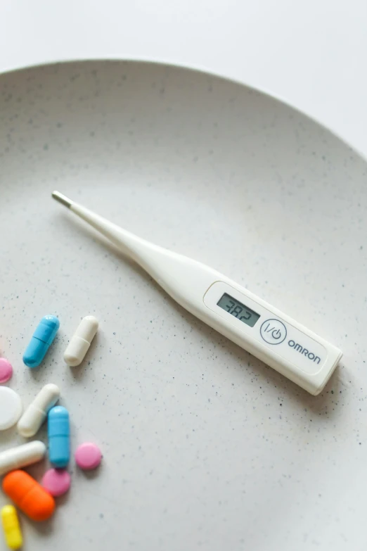 a white plate topped with pills and a digital thermometer, superpop ultrabright, fine point pen, white finish, adult