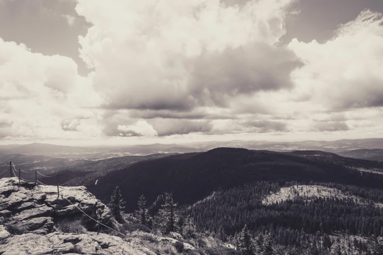 a black and white photo of a person on top of a mountain, by Adam Szentpétery, pexels contest winner, romanticism, black forest, panorama distant view, retro effect, new mexico