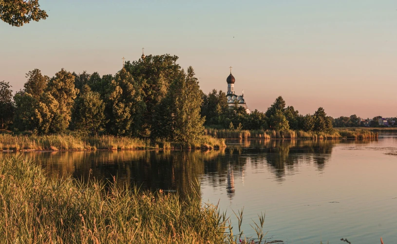 a body of water with a clock tower in the distance, rutkowskyi, nature photo, golden hours, city park