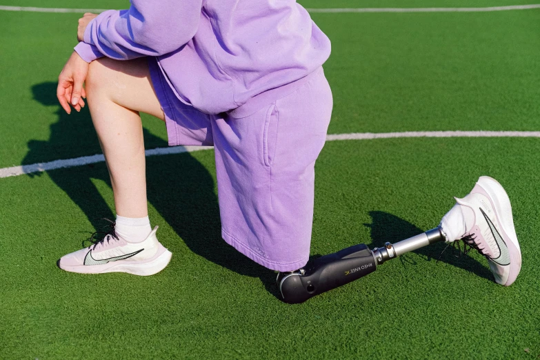 a woman kneeling on a tennis court holding a racquet, by Julia Pishtar, dribble, hurufiyya, robotic prosthetic arm, purple, stretching her legs on the grass, medium close up shot