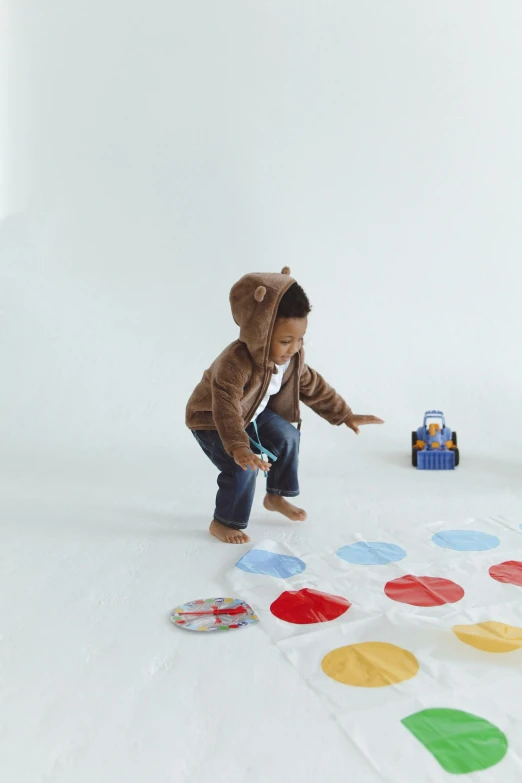 a little boy that is playing a game of hoppy hoppy hoppy hoppy hoppy hoppy hoppy hoppy hoppy hop, interactive art, wearing translucent sheet, on a landing pad, circles, set against a white background