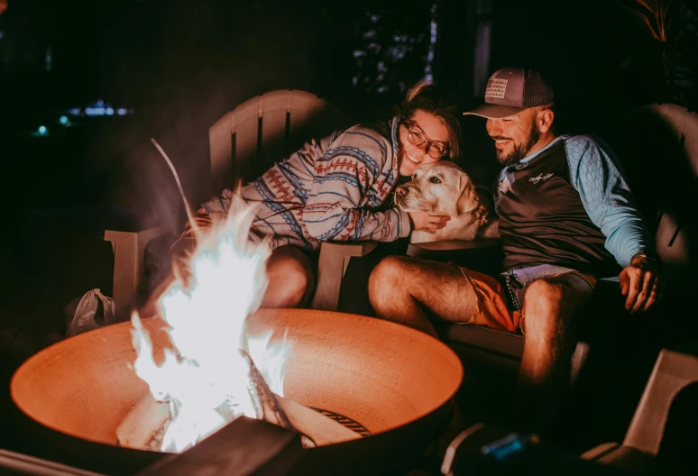 a group of people sitting around a fire pit, a portrait, pexels contest winner, with dogs, romantic mood, husband wife and son, glamping