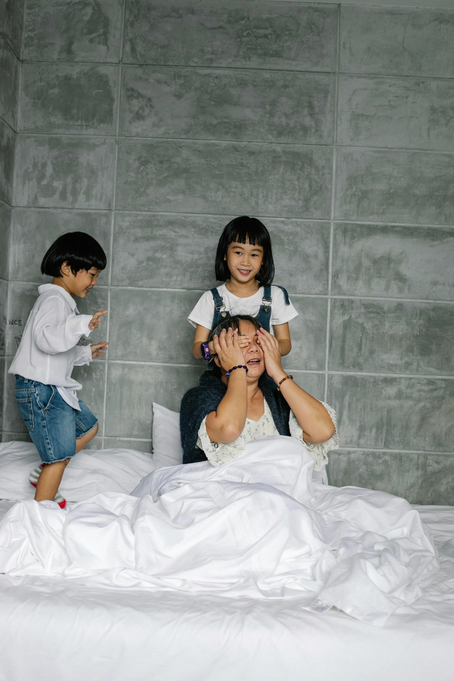 a man sitting on top of a bed next to two small children, by Basuki Abdullah, pexels contest winner, bedhead, yanjun chengt, playful!!!, white sheets