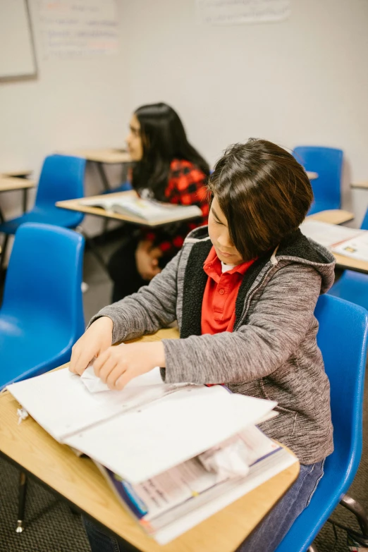 a group of students sitting at desks in a classroom, by Nicolette Macnamara, black haired girl wearing hoodie, thumbnail, studying, jin kim