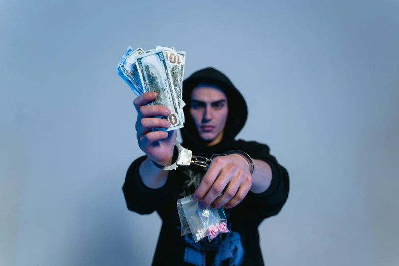 a man holding a bunch of money in his hand, by Niko Henrichon, pexels contest winner, hyperrealism, an edgy teen assassin, avatar image, icy, handcuffed